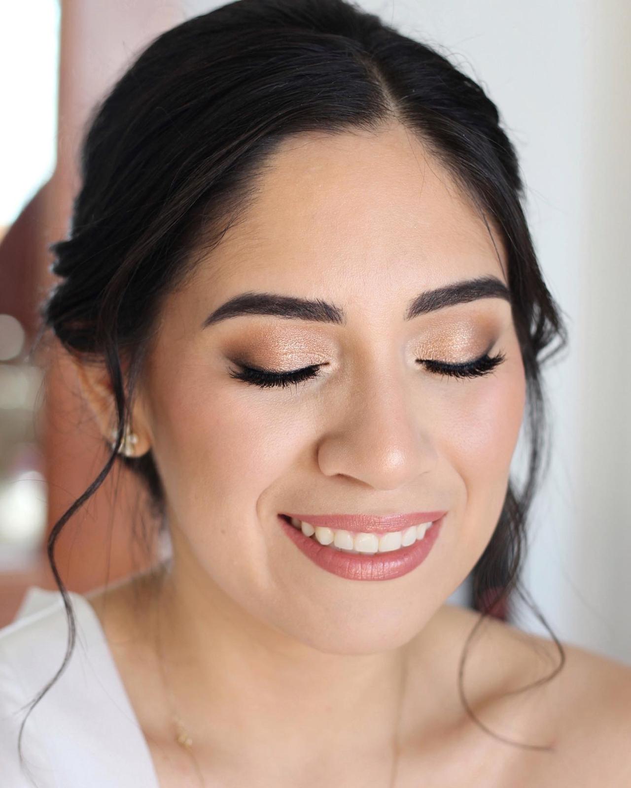 Novia sonriendo con sombra dorada y pestañas